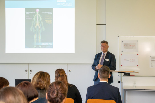 Dr. med. Dirk Heinicke, Chefarzt der Klinik Bavaria Zscheckwitz steht vor sitzenden Zuhörern und hält einen Vortrag zum Thema „Warum gerade ich? – Krankheitsbewältigung und berufliche Entwicklung“.